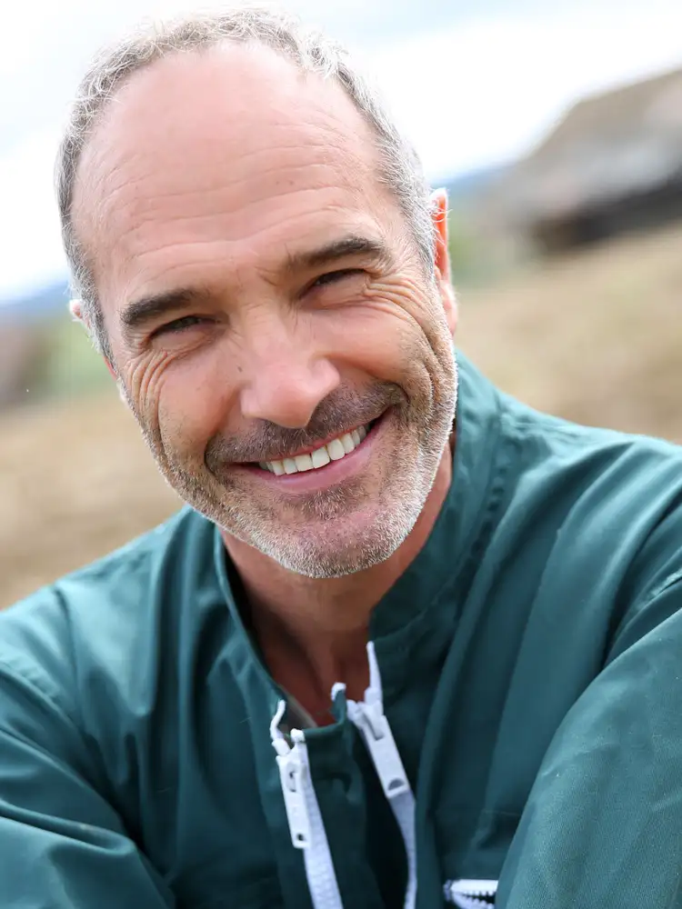A typical candidate showing hair loss and ideal for hair growth treatment. Man in his light-weight rain jacket outside.